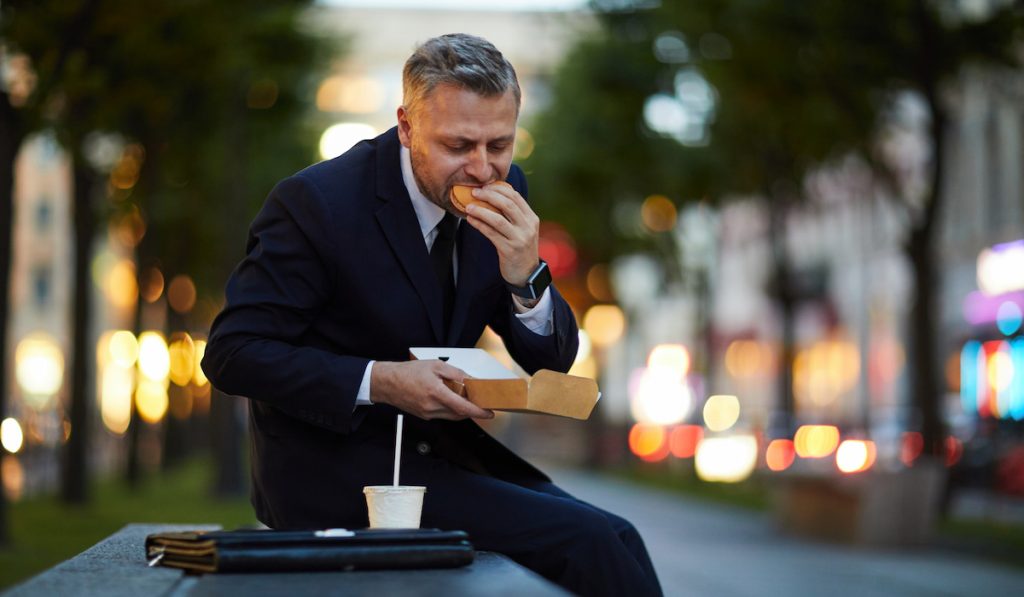 man eating in a hurry at a park