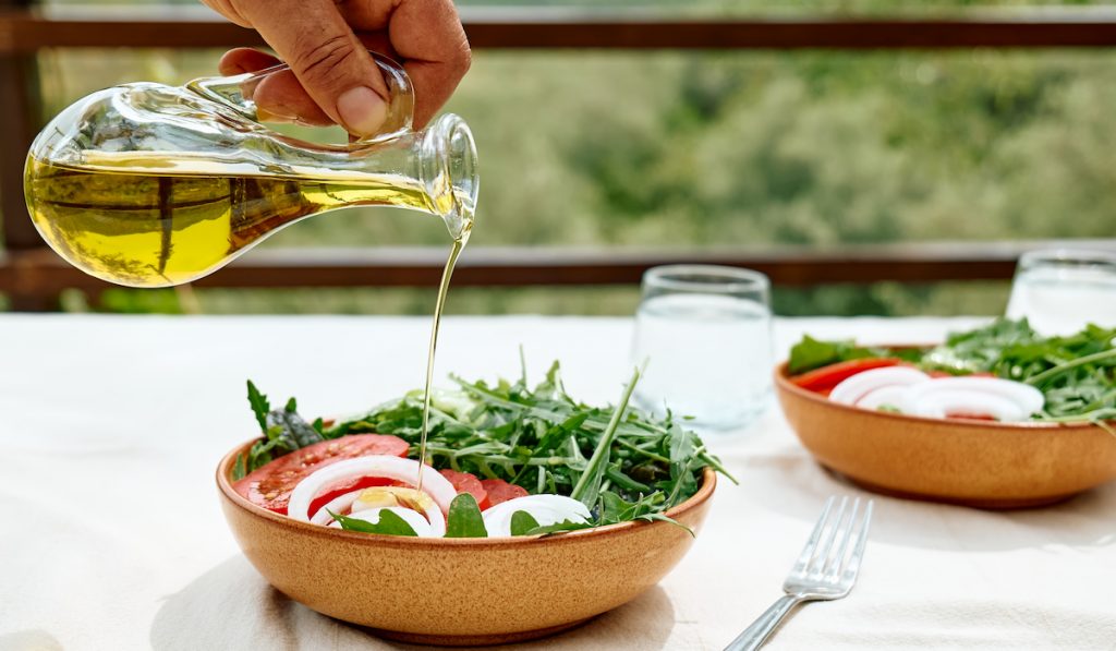 pouring olive oil to salad