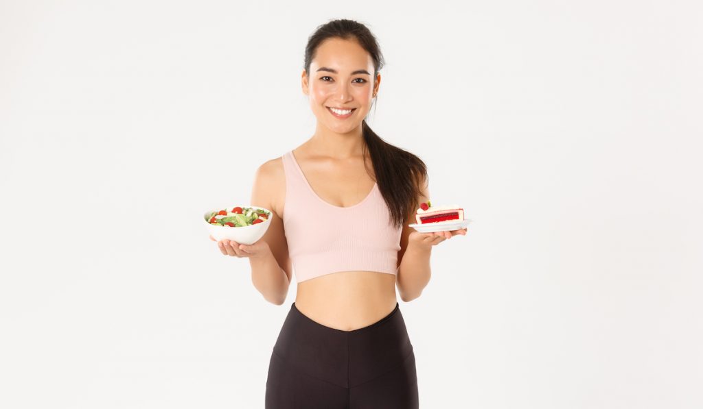 diet coach holding a salad and a slice of cake 