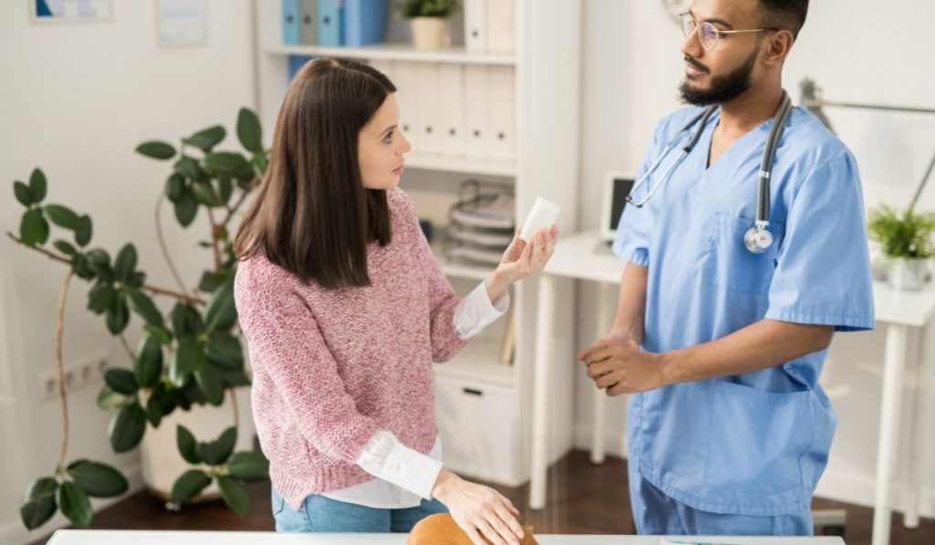 doctor prescribing a medicine to a woman during check up - ee220321