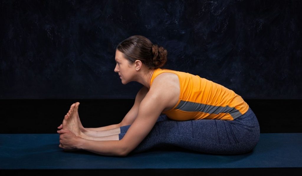 woman wearing orange razor back doing Ashtanga Yoga - ee220401