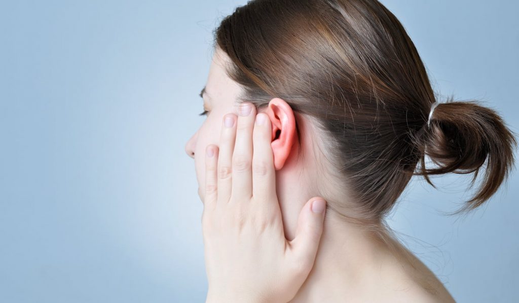 woman holding her inflamed ear